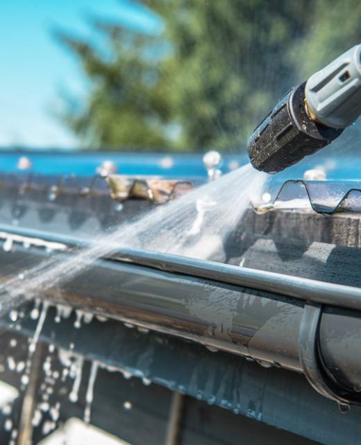 Spring Rain Gutters Cleaning Using Pressure Washer. Closeup Photo.